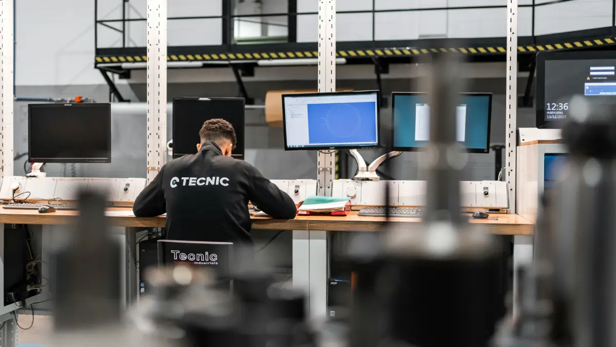 Technolog przy stanowisku komputerowym w hali produkcyjnej