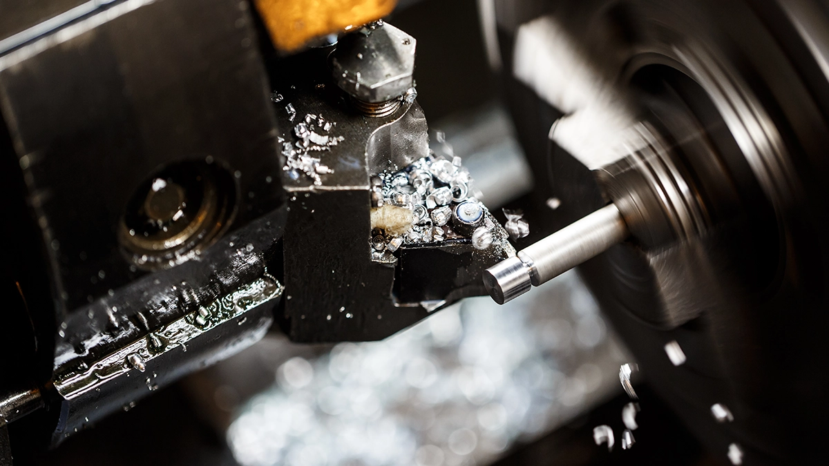 Turning on a CNC lathe: indexable tool and chips at the machined shaft
