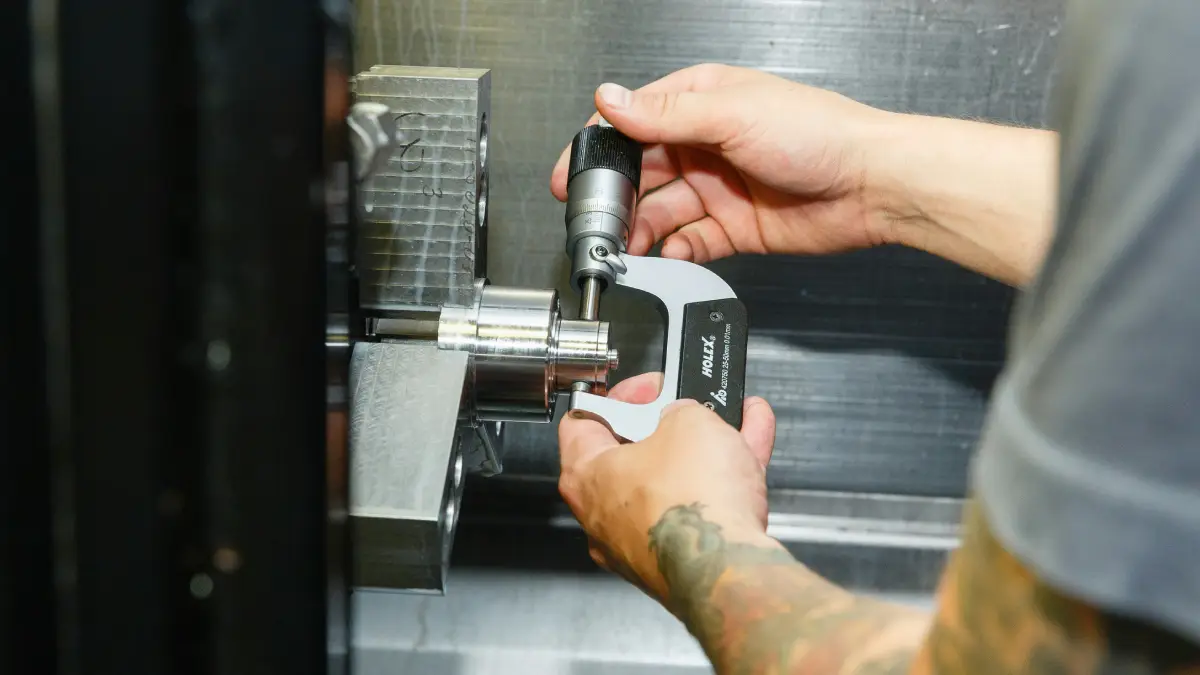 Pomiar toczonego detalu mikrometrem w uchwycie tokarki CNC