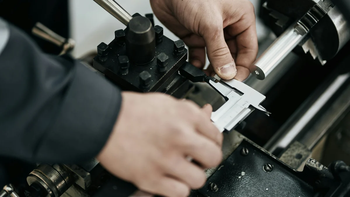 Messen mit dem Messschieber am Werkzeughalter der Drehmaschine, im Futter eine gedrehte Aluminiumstange